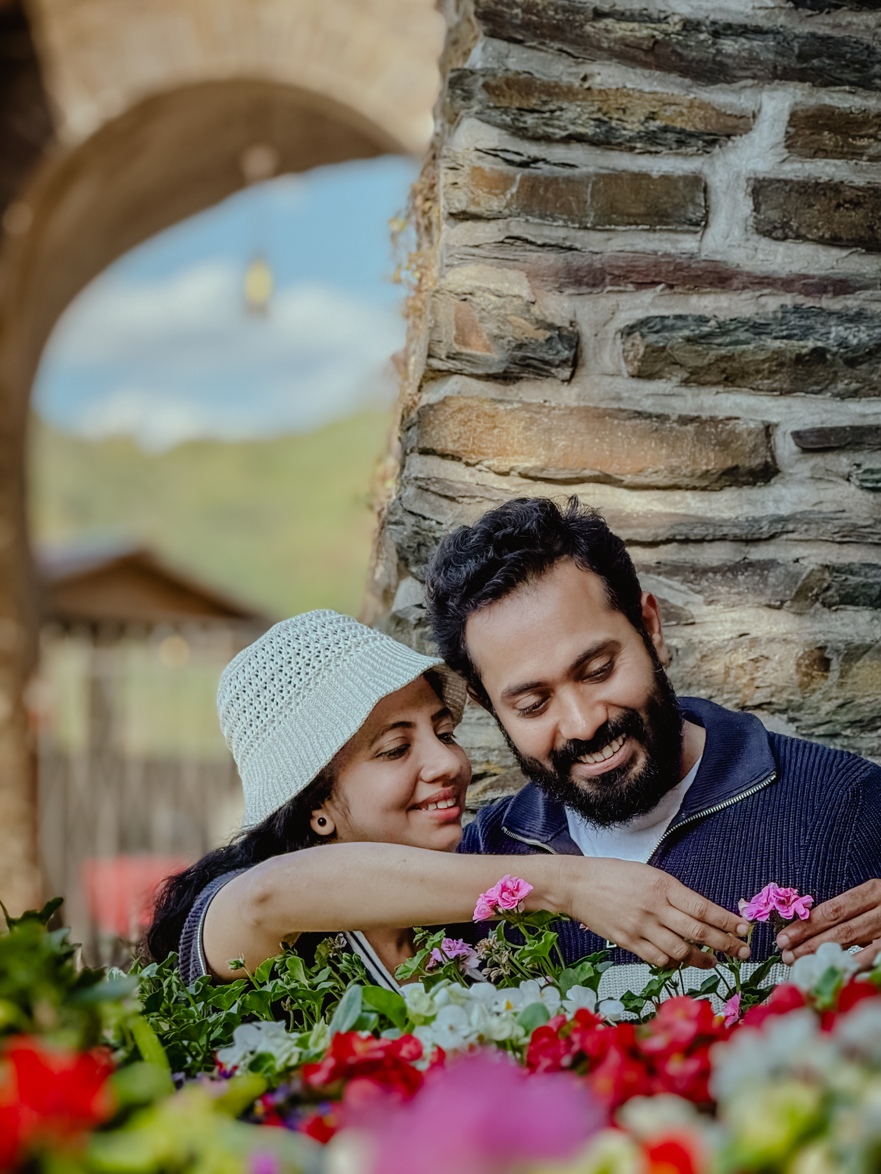 Abhilash and Megha smiling together beside a flower bed